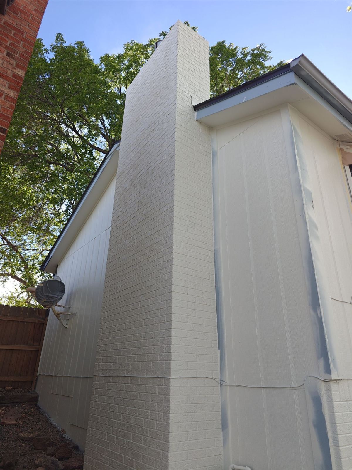 Painter working on siding, brick and trim on a home exterior