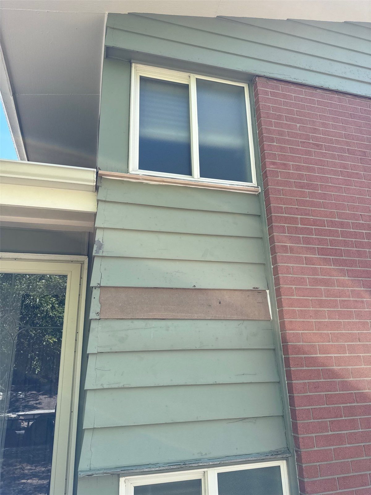 Before: the same siding corner showing cracked, warped and patched boards