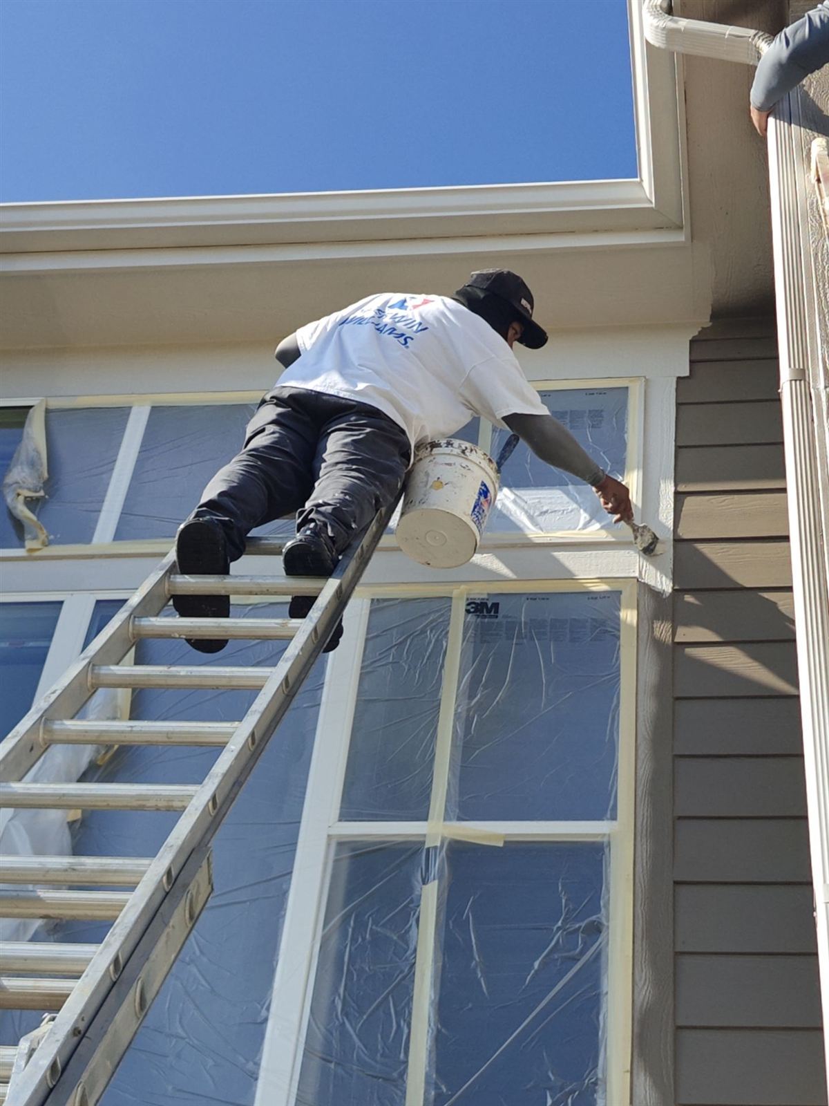 Painter applying trim paint on a home exterior